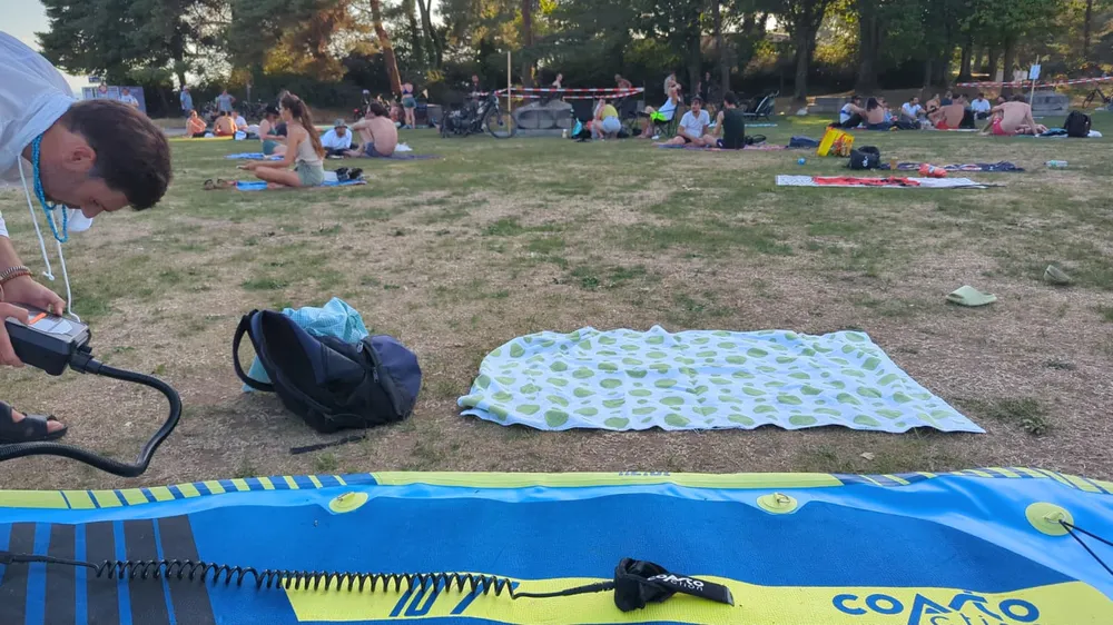 Picnic blankets and a paddleboard by the lake during the ApéroExpats beach party
